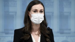Statsminister Sanna Marin sa tidigare under måndagen att paragraferna tas i bruk i tillämpliga delar och inte fullt ut. Statsminister Sanna MArin i närbild med munskydd på sig.