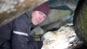 Henri Heikkinen upptäcker att någon annan också varit inne i grottan i Vestervik. Det är roligt, däremot är det mindre roligt att han hittar lite plastskräp i grottan. En man inne i en liten grotta inne i ett berg. Takhöjd cirka en meter.