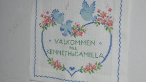 Ett av Camillas många korsstygnsarbeten. ett korsstygnsarbete där det står välkommen till kenneth och camilla