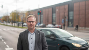 Niclas Grönholm Direktören för den svenska servicehelheten vid sektorn för fostran och utbildning, Niclas Grönholm, står ute framför en väg. Det är höst. En bil kör förbi, Grönholm ser allvarsam ut och tittar åt höger.