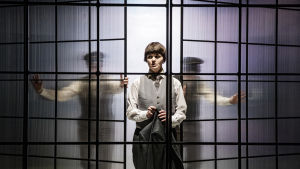 Den passiva herr Bartleby (Joanna Haartti) blev ett olösligt problem för sin chef i pjäsen I would prefer not to, som spelades på Svenska Teatern 2018. En skådespelare i vitt står mellan två glasväggar som skjuts på plats av suddiga gestalter bakom väggarna.
