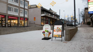 I väntan på sommaren. Glassreklam på golvyta av vitaktig sten, inga människor.