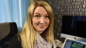 Mikaela Pada vid sitt främsta arbetsredskap, datorn. Blond kvinna med rosa scarf