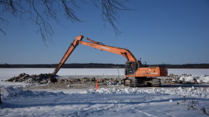 Raseborgs stad har försökt förbättra vattenkvaliteten vid stranden på olika sätt. Grävmaskin som gräver på en sandstrand på vintern när det är snö.