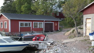 Byastranden på Brännskär söder om Nagu. Brännskärs strand med båtar och uthus och bostadshus i bakgrunden