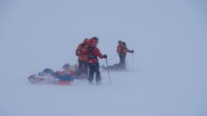 När det stormade ordentligt gick det inte att prata med varandra. Fyra personer iklädda tjocka vinterkläder. De skidar och släpar pulkor efter sig. Det enda som syns runt omkring är snö. Allt är vitt. Det är storm.