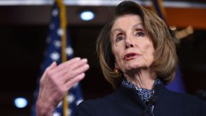 Demokraternas Nancy Pelosi återfår idag posten som talman i representanthuset. Porträttfoto av leende Nancy Pelosi med högerhanden i vädret.