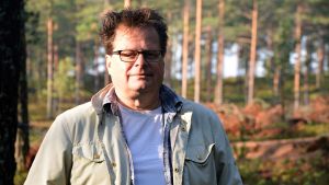 Arkeolog Jan Fast leder utgrävningarna på Hangö udd. Man står i skogen. Solen skiner.
