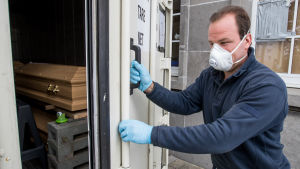 Dödligheten i Belgien har ökat betydligt. En arbetare vid kyrkogården i Uccle öppnar dörren till en nedkyld container med kistor.