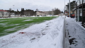 I Ekenäs värms inte konstgräsplanen upp utan den hålls snöfri med andra metoder. I vintras var det ändå en utmaning. Centrumplan i Ekenäs den 5 mars 2018 kvart över två på eftermiddagen. Litet grön konstgräsplan, men ännu är det snö kvar.