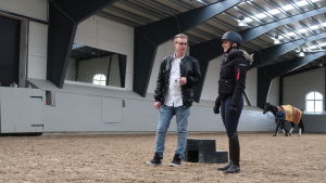 Mikkonen och von Wendt har planerat anläggningen på ridhusets tak en lång tid en kvinna med ridhjälm och en man i svart rock diskuterar mitt i ett ridhus. En häst blir ledd i bakgrunden