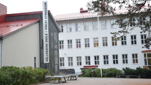 Eleverna kommer tillbaka till Källhagens skola den 14 maj. Gymnasiestuderandena hålls ändå borta från skolområdet. En stor skola i vit betong och rött tak. Många fönster. Står Källhagens skola och Virkby gymnasium.