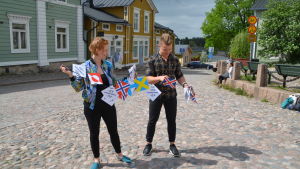 Två personer står i Borgå gamlastad och reder upp en bunt med vimplar.