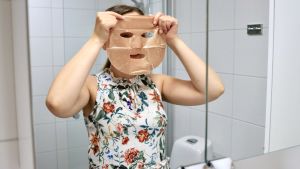 Arkmaskerna finns i olika material och färger. En kvinna som håller upp en ansiktsmask framför ansiktet