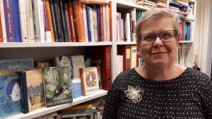 Barnbokforskaren Mia Österlund och Muminhyllan i hennes arbetsrum. Barnboksforskare Mia Österlund och muminhyllan.