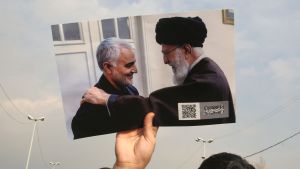 En man håller upp en bild av den Irans högsta religiösa ledare Ayatollah Ali Khamenai tillsammans med den iranska generalen Qasem Soleimani. Demonstration i Teheran 3.1.2020 En man håller upp en bild av den Irans högsta religiösa ledare Ayatollah Ali Khamenai tillsammans med den iranska generalen Qasem Soleimani. Demonstration i Teheran 3.1.2020