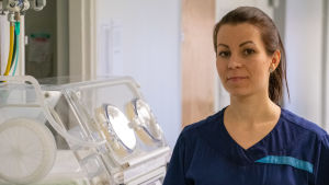 Jenny Forsström har tidigare jobbat på Borgå BB. I höstas började hon jobba i Kotka och tycker att det är samma goda stämningen som i Borgå. Jenny Forsström tittar in i kameran och ler. Hon står ute i korridoren.