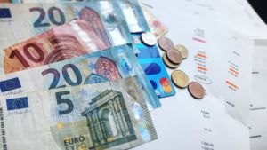 Euroseteleitä, kolikoita ja papereita, jossa näkyy eurosummia