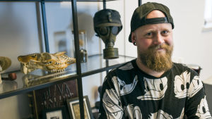 Själv gillar Nico Ström traditionella tatueringar. Tatueraren Nico Ström framför en hylla med en gasmask och fotografier.