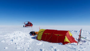 Den som hamnar i trubbel kan bli hämtad med helikopter. Ett tält och en helikopter på Grönland. Det enda som syns är snö.