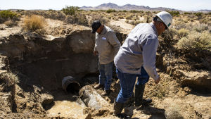 Två män i Kalifornien inspekterar skadorna av en vattenledning som gått sönder på grund av jordbävning.