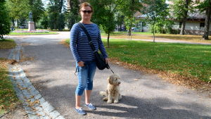 Maija Sairanen önskar mer information om gärningsmännen. En kvinna med en hund i koppel står i en park.