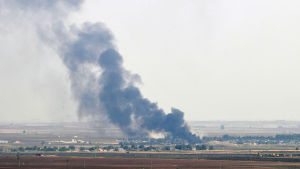 Den syriska gränsstaden Rads al-Ain brinner. På bilden syns staden på långt avstånd och svart rök som stiger upp från den. 