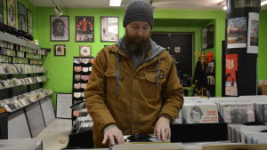 Fredrik Johansson föredrar vinyl och kassett då han ska lyssna på musik. En man med skägg bläddrar bland skivorna.