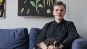 Ordvitsar flyger runt i luften hela tiden, det är bara att plocka ner dem, säger Alfred Backa. Komikern Alfred Backa sitter i en soffa med sin katt i famnen.