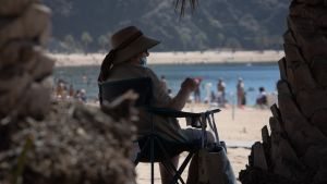 Stränderna har öppnats igen i Spanien Dam som sitter i skuggan på en strand på Teneriffa