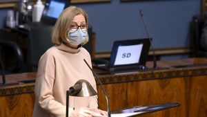 Då Anneli Kiljunen (SDP) talade måste talman Anu Vehviläinen lugna ned stämningen i riksdagssalen. Riksdagsledamot Anneli Kiljunen står i en talarstor. Hon har munskydd.