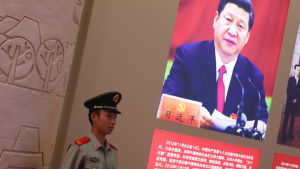 En polis står vakt vid en affisch med presiden Xi Jinping