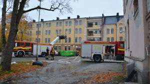 Eftersläckningsarbetet pågår. Brandbilar och brandmän framför en gammal gul stenbyggnad i centrum Åbo.