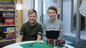 Kevin Lintula och Milton Appel trivs i nyrenoverade skolan. Två pojkar sitter vid ett bord. På bordet finns en kortpacke och pokerchips.