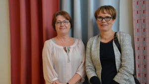 Gunilla Fröberg och Kira Exell-Paakki säger att yngre anställda vid Folkhälsan säkert kunde samarbeta med unga för att sprida intresset för närvårdaryrket. Kanske bloggar och vloggar kunde hjälpa? gunilla fröberg och kira exell-paakki står med färgglada gardiner i bakgrunden