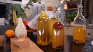 Festen kan börja. Servera kombucha som en öl eller cider väl avkyld. Kombucha i fyra glasflaskor på köksbordet.