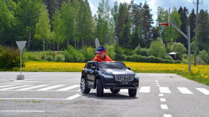 Veijo Paasilas barnbarn Aatu Paasila kör ivrigt omkring i trafikparken utanför byns café. En liten pojke som kör en leksaksbil.