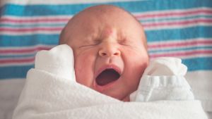 Rekommendationen att låta spädbarn sova på rygg istället för på mage har visat sig minska risken för plötslig spädbarnsdöd. Baby gäspar.
