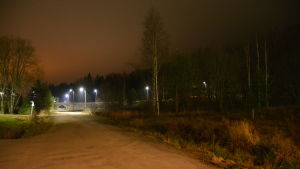 Buskaget till höger på bilden kan omvandlas till skolgård om Söderkulla skola byggs vid Kompassvägen. Gångväg upplyst av orange gatubelysning.
