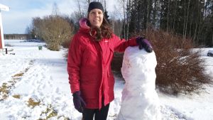 Anki Stenkull-Aura råder familjer till barn med specialbehov att göra så som det fungerar bäst för den egna familjen. Här har barnen byggt en snögubbe på gården efter skoldagen. Kvinna ute bredvid snögubbe.