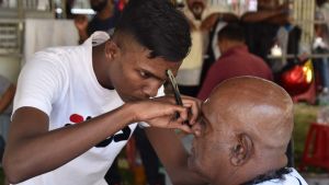 En stor del av barberarna i Malaysia är gästarbetare från Indien. De jobbar i populära, billiga frisörsalonger som nu är stängda på grund av viruskrisen. En barberare rakar en kund i Georgetown i Malaysia