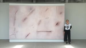 Nina Roos bredvid en av målningarna i sviten Lucid. Målning och kvinnlig konstnär i ett galleri.