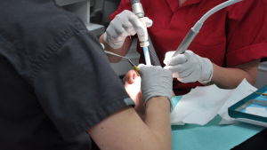 En patient i tandläkarstol får behandling av tandläkare.
