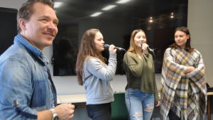 Tjejer från Nordahl Grieg videregående skole, Bergen, Norge övar under ledning av Fredrik Furu. Musikern Fredrik Furu lyssnar till tre sjungande tjejer från Nordahl Grieg videregående skole, Bergen, Norge