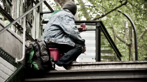 I Helsingfors har man också svårt att få avdelningsplatserna att räcka till. Kille i en trappuppgång på huk med kaffemugg i handen.