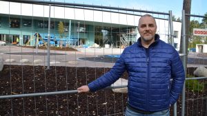 Niklas Läckström framför väggen där skoleleverna kommer att gå in till klassrummen. Niklas Läckström framför Vårberga bildningscentrum.