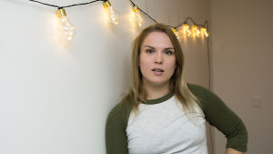 Sanna Helander i en lägenhet som antagligen kommer att synas i filmen Blinkers. Sanna Helander som lutar sig mot en vägg. På väggen hänger små glödlampor på en girlang.