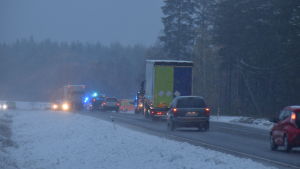 Arkivbild från olycksmorgonen. Bilar står i kö på en väg. I bakgrunden syns blåljus som lyser.