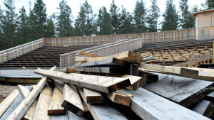 Totalt 15 000 meter virke har använts till att bygga läktaren och scenen i Harparskog. En hög med bräder med spik i ligger framför en läktare som håller på att rivas.