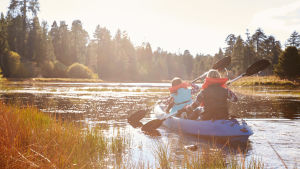 Det finns ett stort utbud av fritidsaktiviteter på Kimitoön. En flicka och en kvinna paddlar i en lugn naturskön vik i solsken.